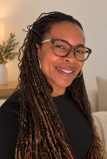 Simone Kirkpatrick, smiling, in a black top and tortoiseshell glasses